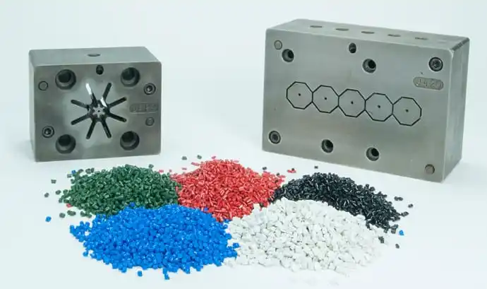 2 plastic extrusion molds behind green, red, blue, black, and white polymeric compounds